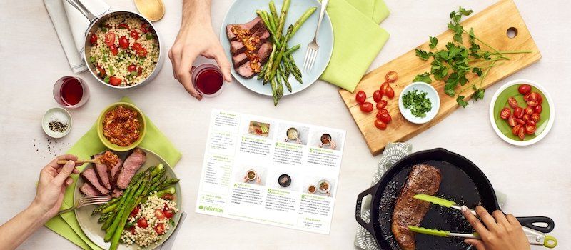 Several dishes with ingredients along with utensils and a cast iron pan