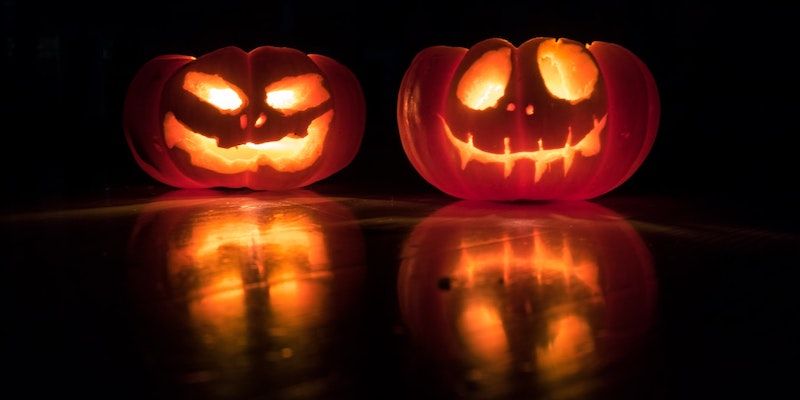 Two carved pumpkins lit up in a dark room