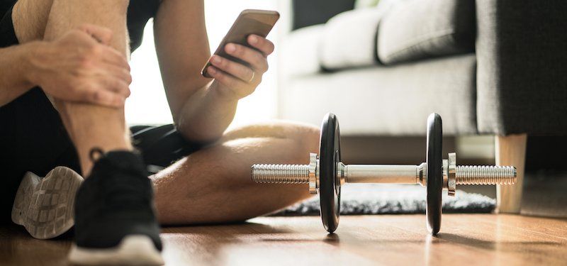 Man uses phone while next to workout equipment in living room