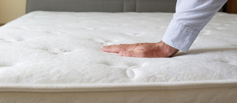 man testing firmness of mattress
