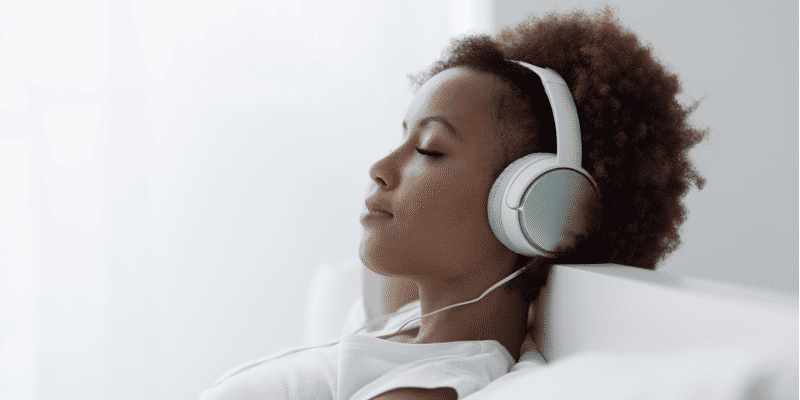 woman listening to music with headphones in bed