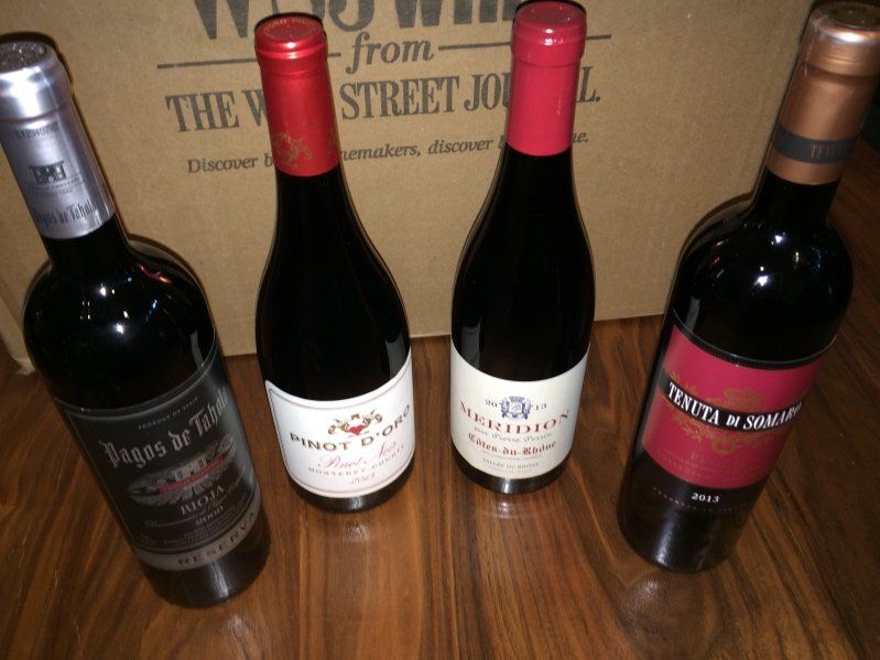 A photo of four dark wine bottles that are unopened