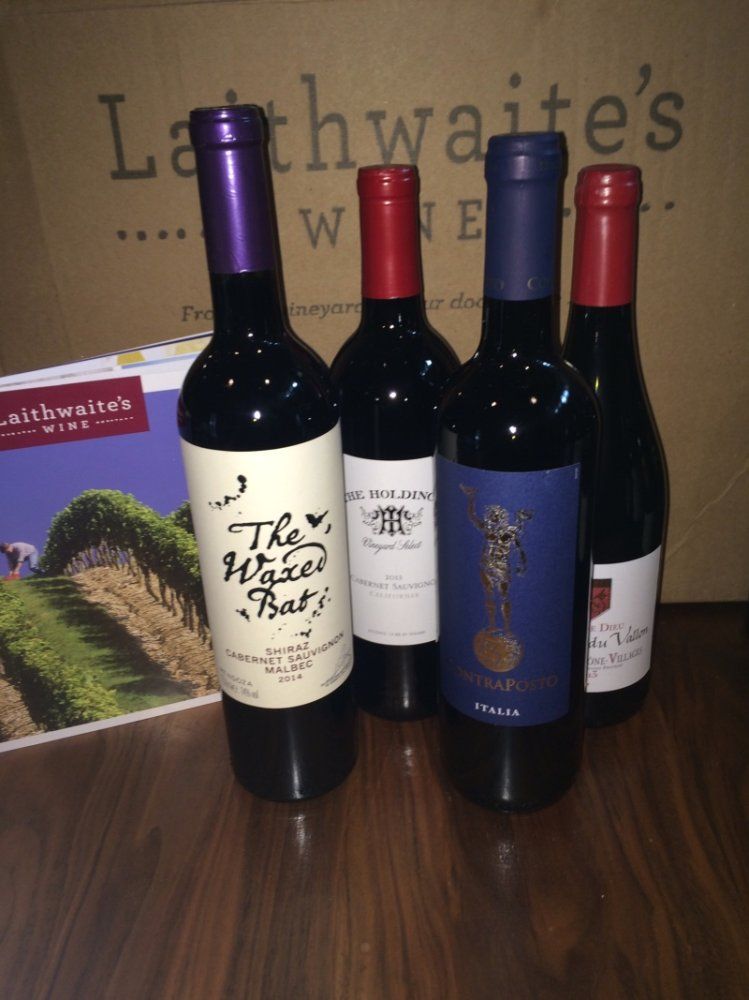 Four bottles of wine standing next to the Laithwaite's box and wine newsletter