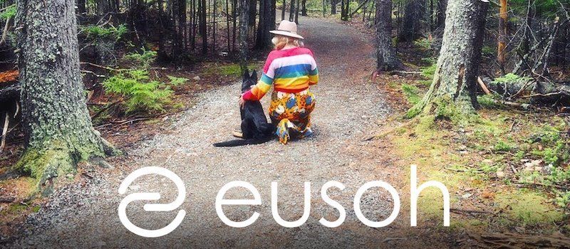 Woman and dog on a forest trail with the word "Eusoh" at the bottom of the photo