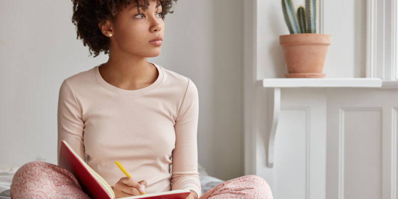 woman thinking while writing in journal