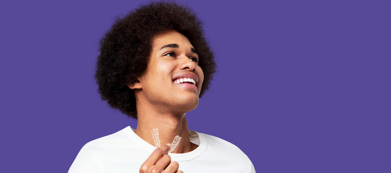 Man smiles while holding aligner