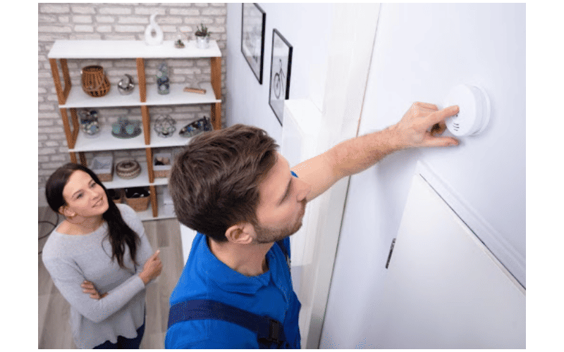 technician adjusting smoke alarm