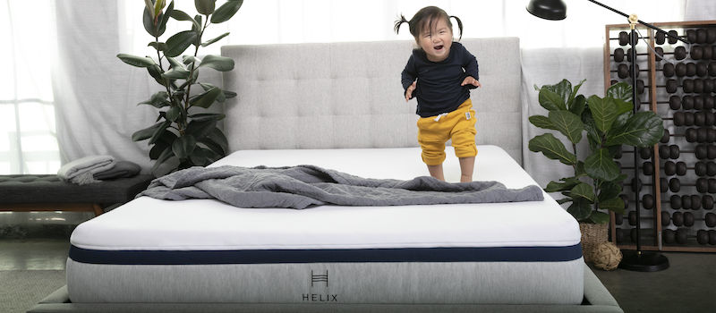 Little girl laughs and jumps on a Helix mattress