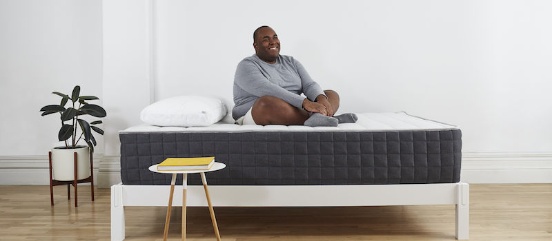 Man sits cross-legged on Helix Plus mattress