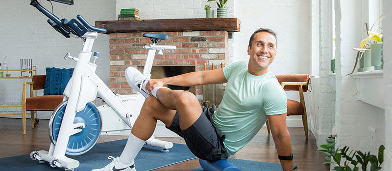 man stretching next to exercise bike