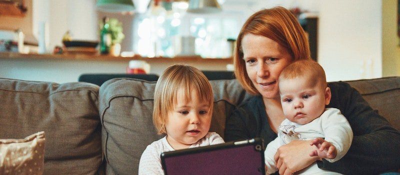 Mom and kids use tablet to watch cartoons