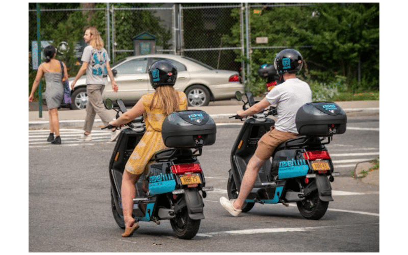 a woman and a man riding electric mopeds