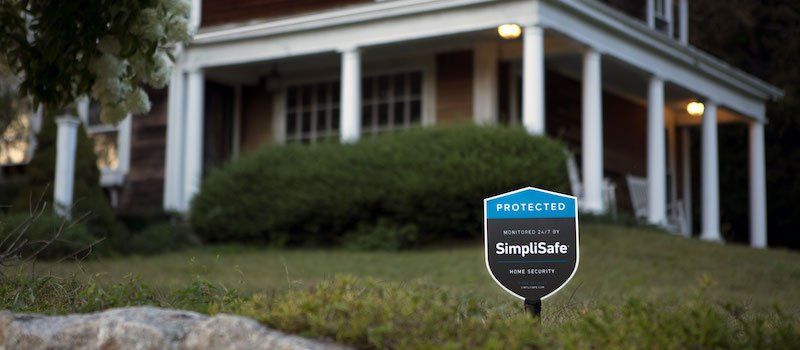 A SimpliSafe sign in the front yard of a home