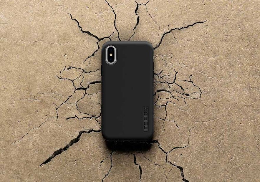 Black cell phone on cement showing cracks around the center